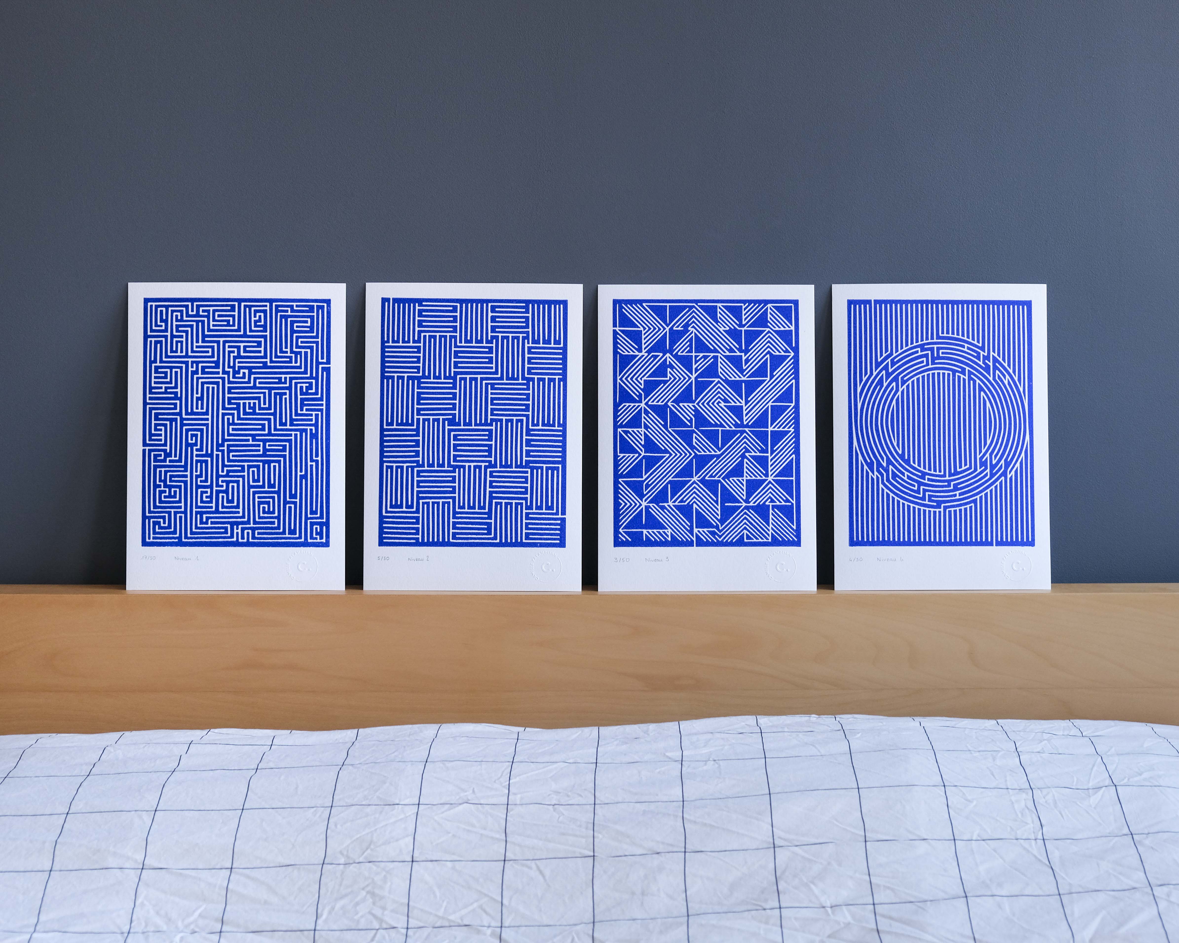 Quatre linogravures bleues affichées sur un mur gris 